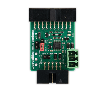 Image of a green circuit board adapter with labeled pins and connectors, designed for interfacing electronic components. It includes components like resistors and capacitors, along with a red switch indicating the power settings. The adapter is identified as a "S7 Adapter" from Segger.